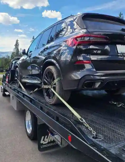 Tow truck assisting stranded SUV at night in residential area after unexpected breakdown