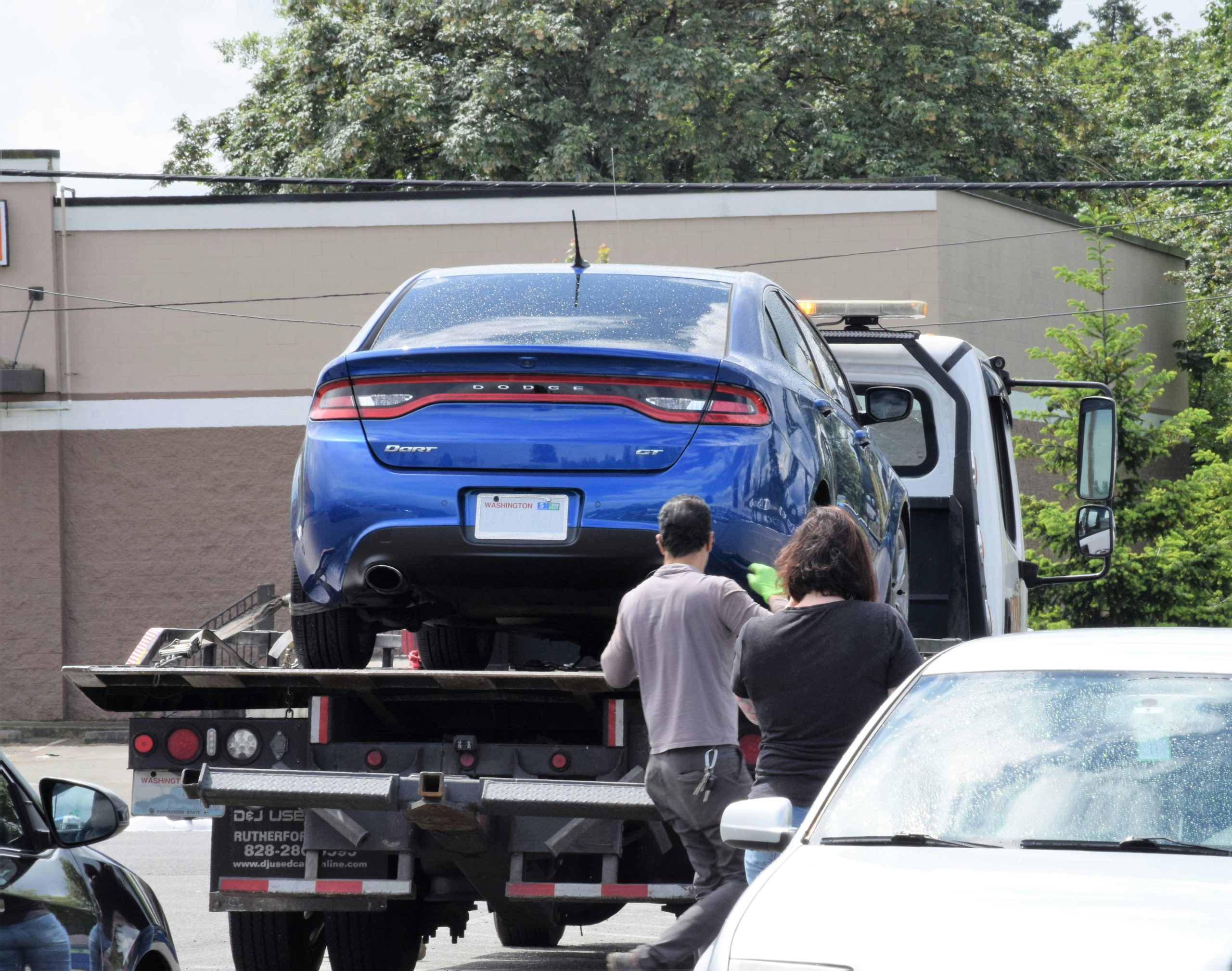 Towing company near me, Tow truck assisting stranded driver with disabled SUV on roadside in Sterling Hills, Tow truck loading disabled SUV outside busy North Westminster shopping center entrance
