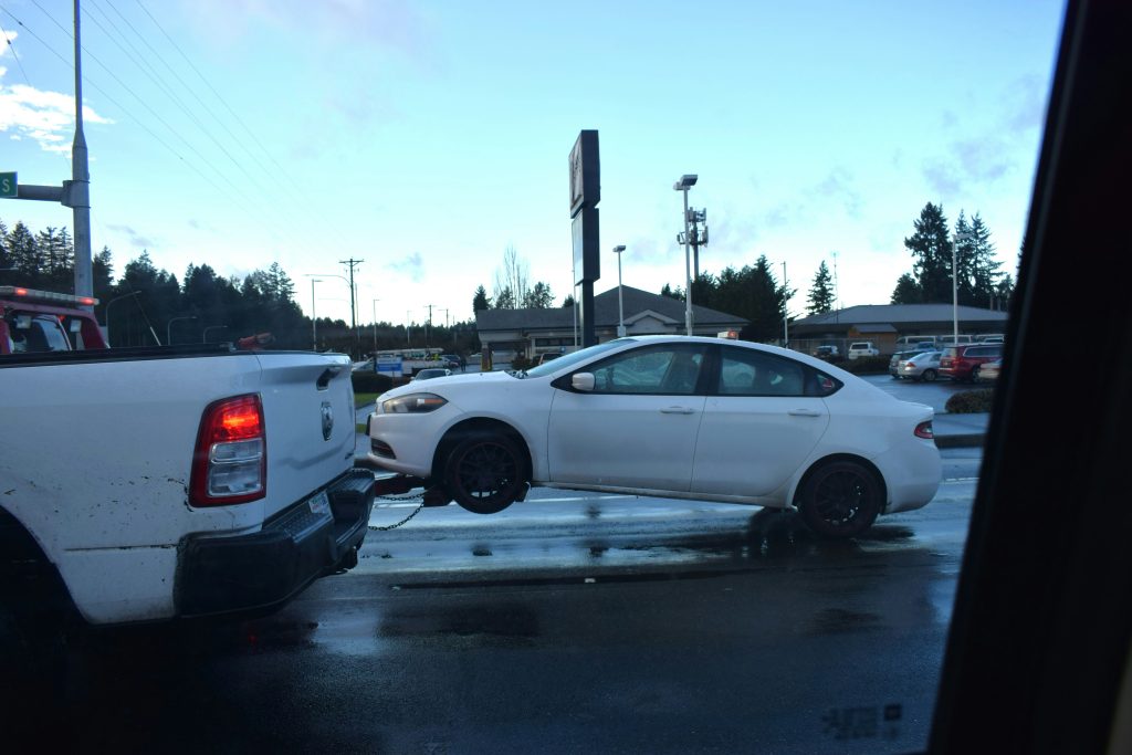 Towing company near me, Tow truck loading disabled pickup truck outside busy roadway in Henderson neighborhood, Skilled tow operator securing vehicle carefully beside busy roadside with professional equipment