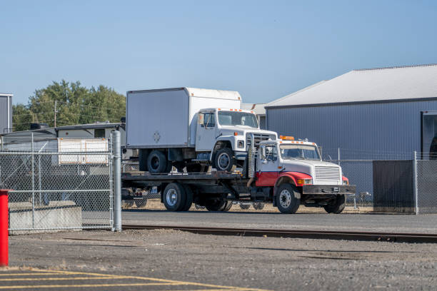 Experienced tow operator securing commercial pickup with careful wheel placement and safety checks, Experienced tow operator securing work van with proper fleet transport equipment, Fleet towing crew loading a disabled commercial van near a Morrison - CO roadside turnout