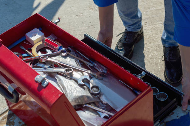 Experienced tow operator securing work truck with toolbox using careful loading and transport checks, Experienced operator securing heavy equipment with chains and trailer tie-downs